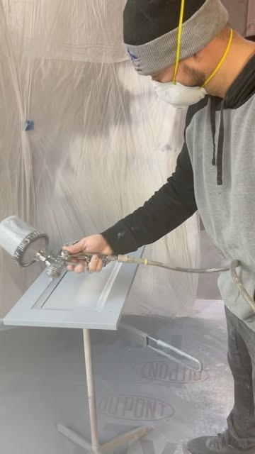 David Sav spraying a cabinet door.