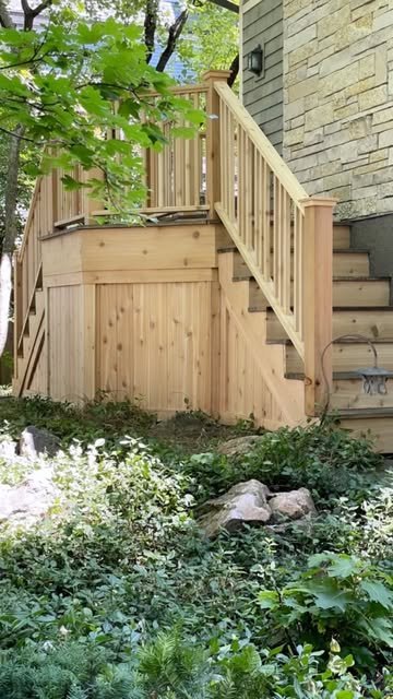 Cedar deck with rails and stairs beside a stone wall.