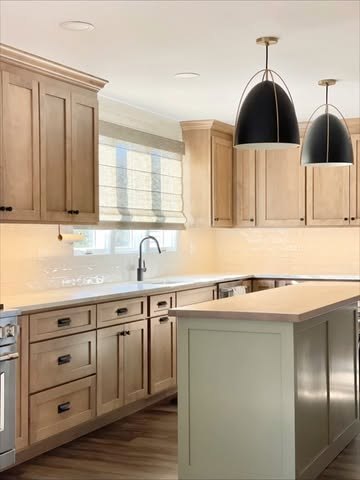Kitchen with natural wood cabinets and a sage painted island.